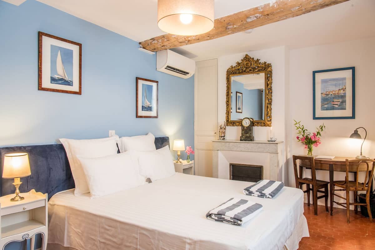 Une chambre d’hôtel équipée d’un lit, d’un bureau, d’une chaise, d’une cheminée et de tableaux encadrés aux murs.