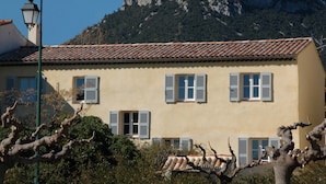 Un bâtiment avec un toit recouvert de tuiles, de nombreuses fenêtres équipées de volets et un lampadaire au premier plan.