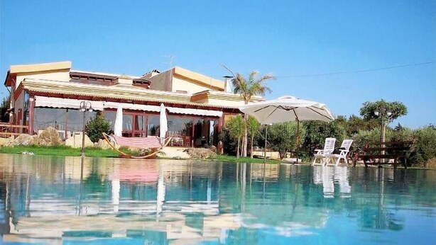 A house with a swimming pool, a covered patio, and a view of the pool. - Agriturismo Le Arcate (Marsala)