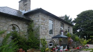 A stone house with a garden, a bench, and a small outdoor seating area. - Disblair House (Aberdeen)