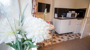 A kitchen with white cabinets, a microwave, and a checkered floor.