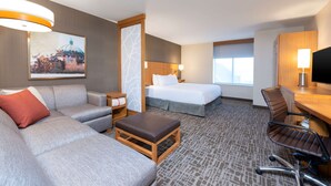 A hotel room with a sofa, a bed, a desk, and a chair. - Hyatt Place Detroit Royal Oak (Royal Oak)