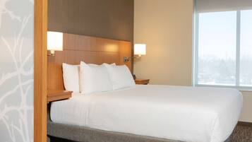 A hotel room with a large bed, wooden headboard, two bedside lamps, and a window with a view.