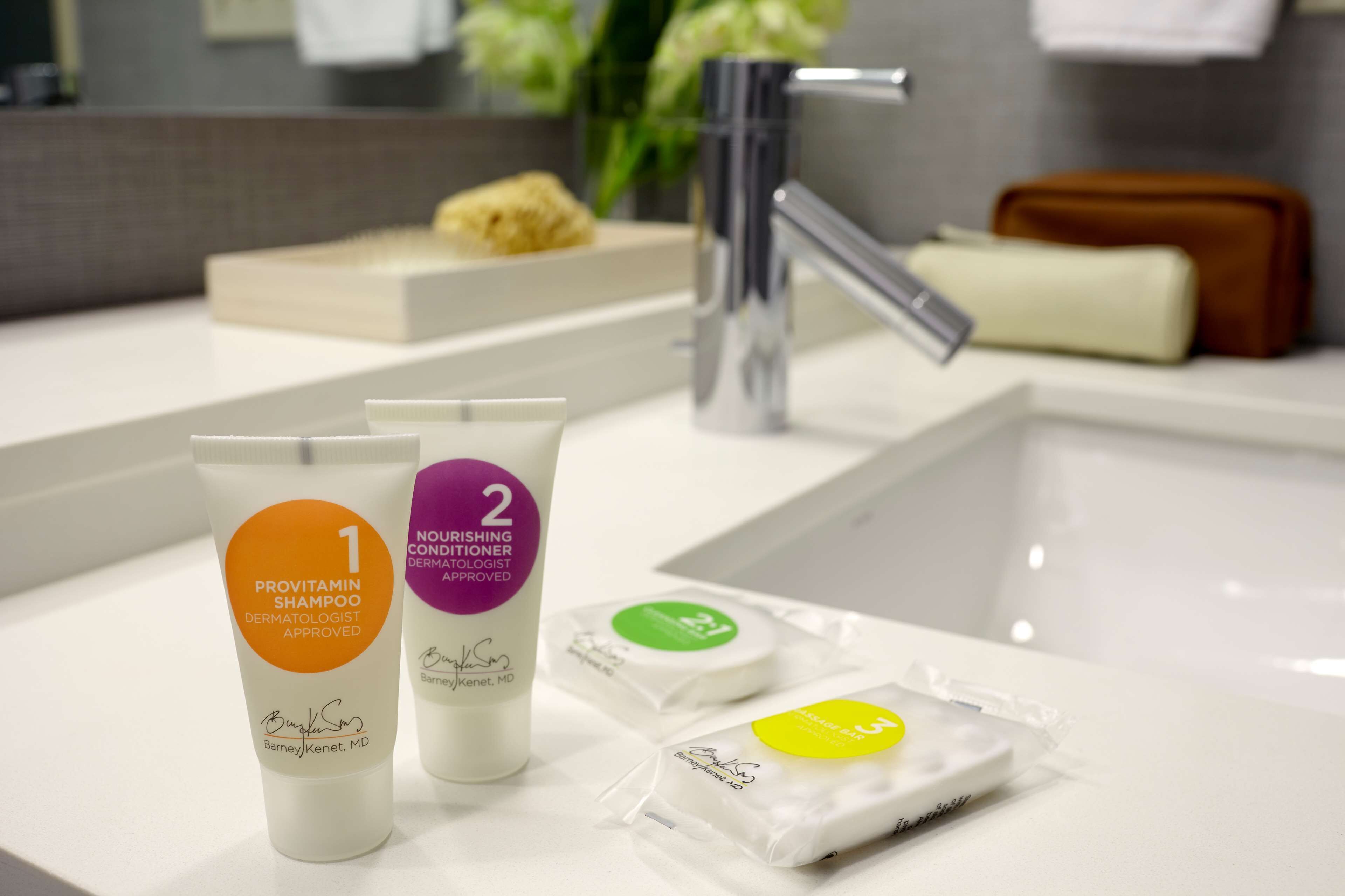 A bathroom counter with toiletries, including two tubes of Provitamin Shampoo and a bar of soap.