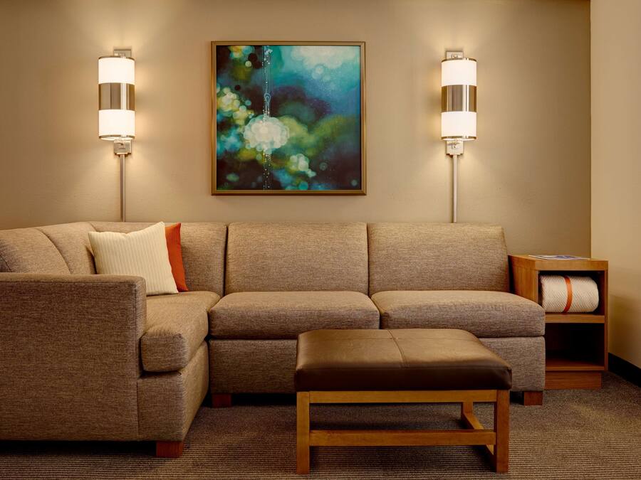 A modern living room with a sectional sofa, a wooden bench, and two wall-mounted lamps.