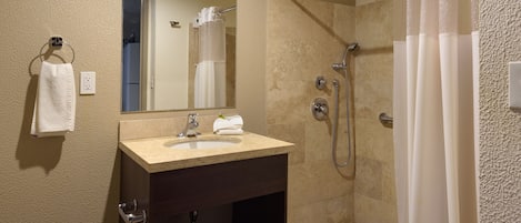 A bathroom with a sink, mirror, and shower.