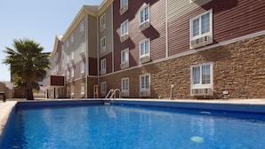 Una piscina con fachada de piedra y múltiples ventanales.