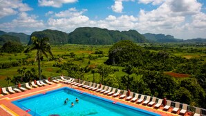 Piscina con lettini e vista su dolci colline e montagne.