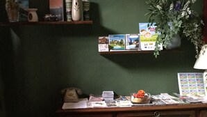 A wooden desk with a glass front, a vase with a plant, and various items on the desk including a telephone, books, and papers.