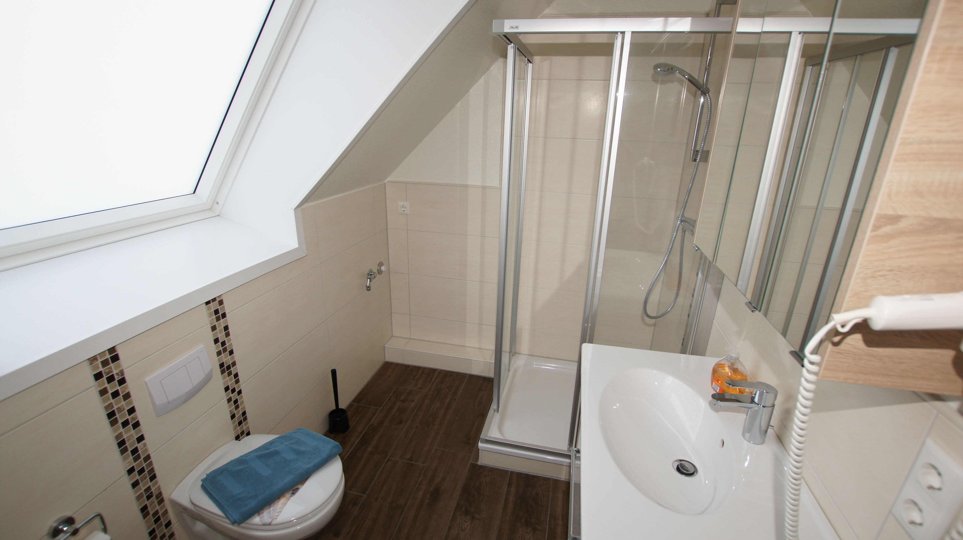 A small, modern bathroom with a shower, toilet, and sink.