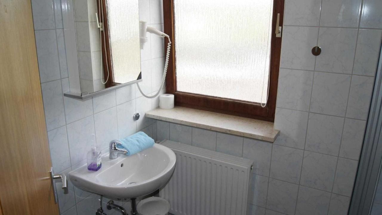 A bathroom with a sink, mirror, towel, and window.
