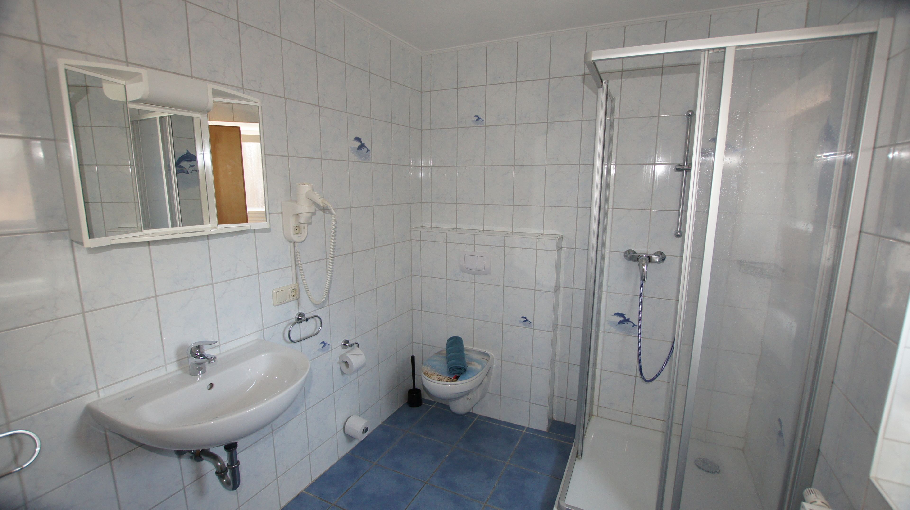 A bathroom with a white sink, a mirror, a toilet, and a glass-enclosed shower.