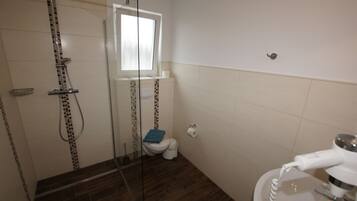 Ein Badezimmer mit Duschkabine, Toilette und Waschbecken, inklusive Föhn.