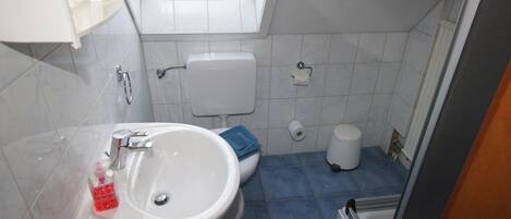 Une salle de bain avec un lavabo blanc, des carreaux bleus, des toilettes et une fenêtre.