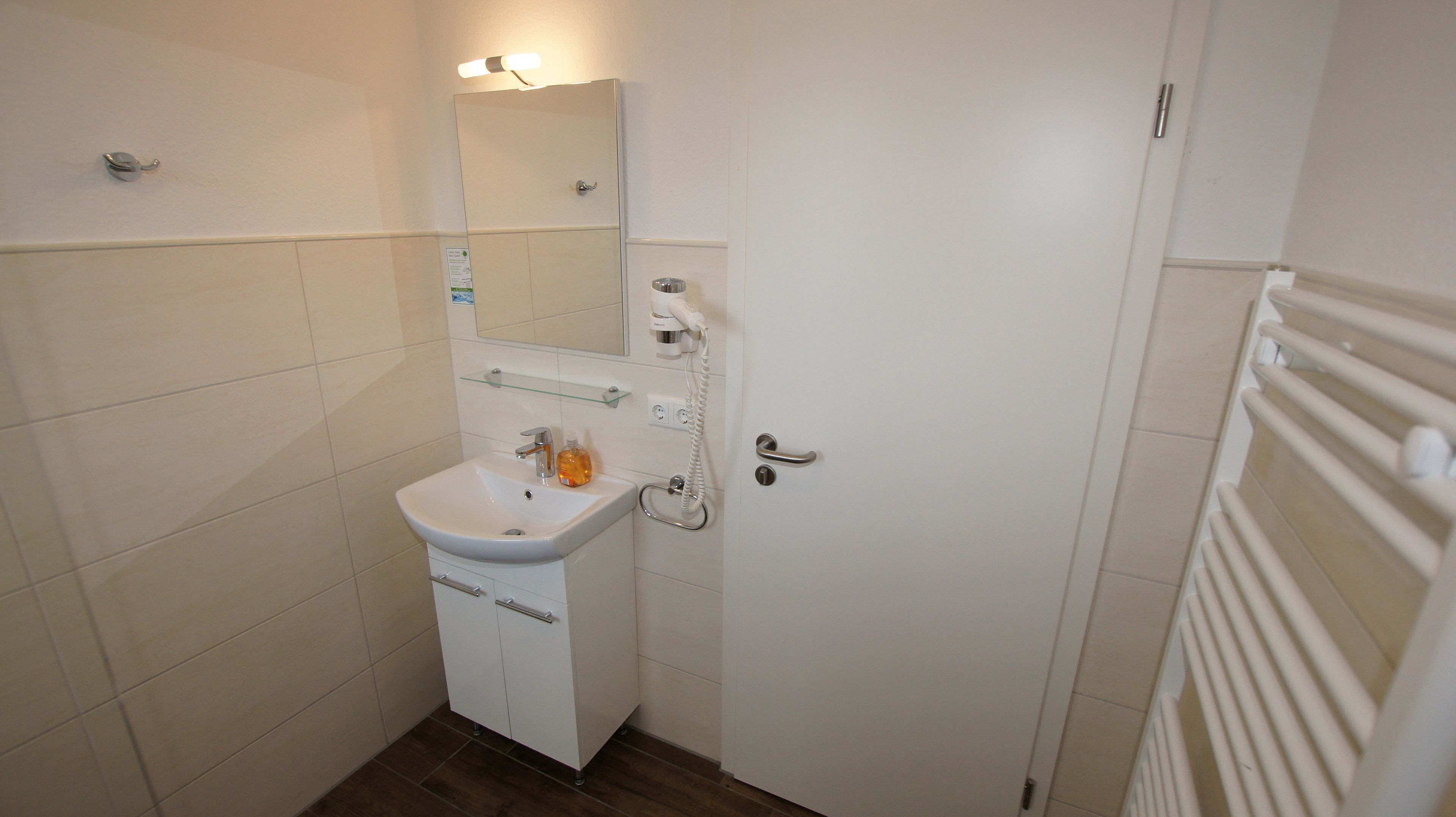 A small bathroom with a white sink, mirror, and towel rack.