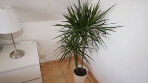 A white bedside table with a lamp and a potted plant. - Hotel Dorfkrug Büsum (Büsum)
