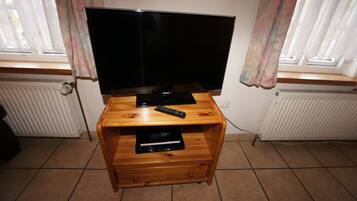 Un mueble bajo de madera con un televisor de pantalla plana, controles remotos y un reproductor de DVD Samsung.