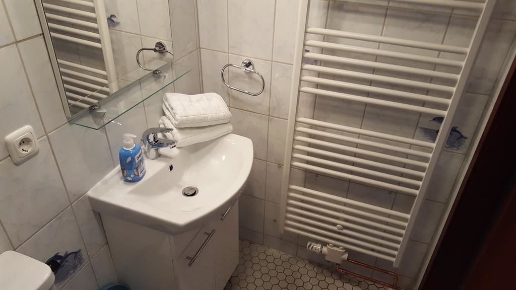 A bathroom with a white sink, mirror, and towel rack.