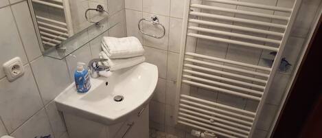 A bathroom with a white sink, mirror, and towel rack.