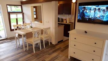 Une cuisine moderne avec un coin repas, un téléviseur fixé au mur et un petit îlot central.