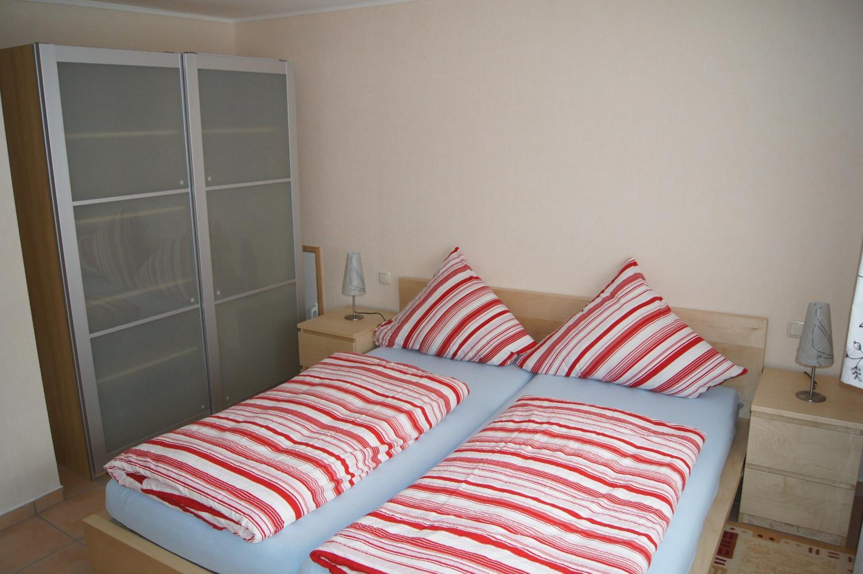 Ein Schlafzimmer mit einem Bett, zwei Nachttischen, einer Lampe und einem Kleiderschrank.