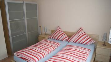 Ein Schlafzimmer mit einem Bett, zwei Nachttischen, einer Lampe und einem Kleiderschrank.