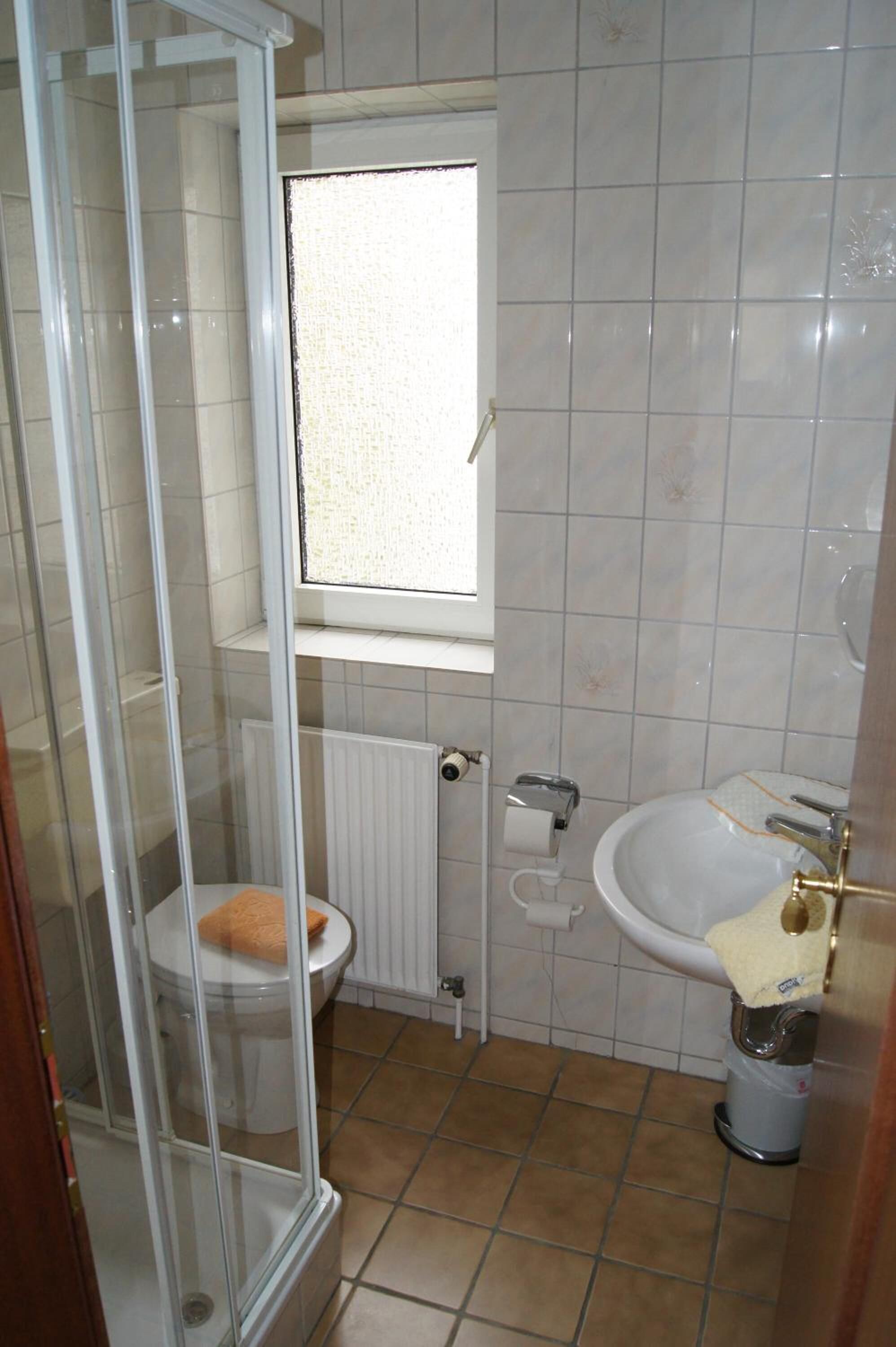 Een badkamer met toilet, wastafel en douchecabine.