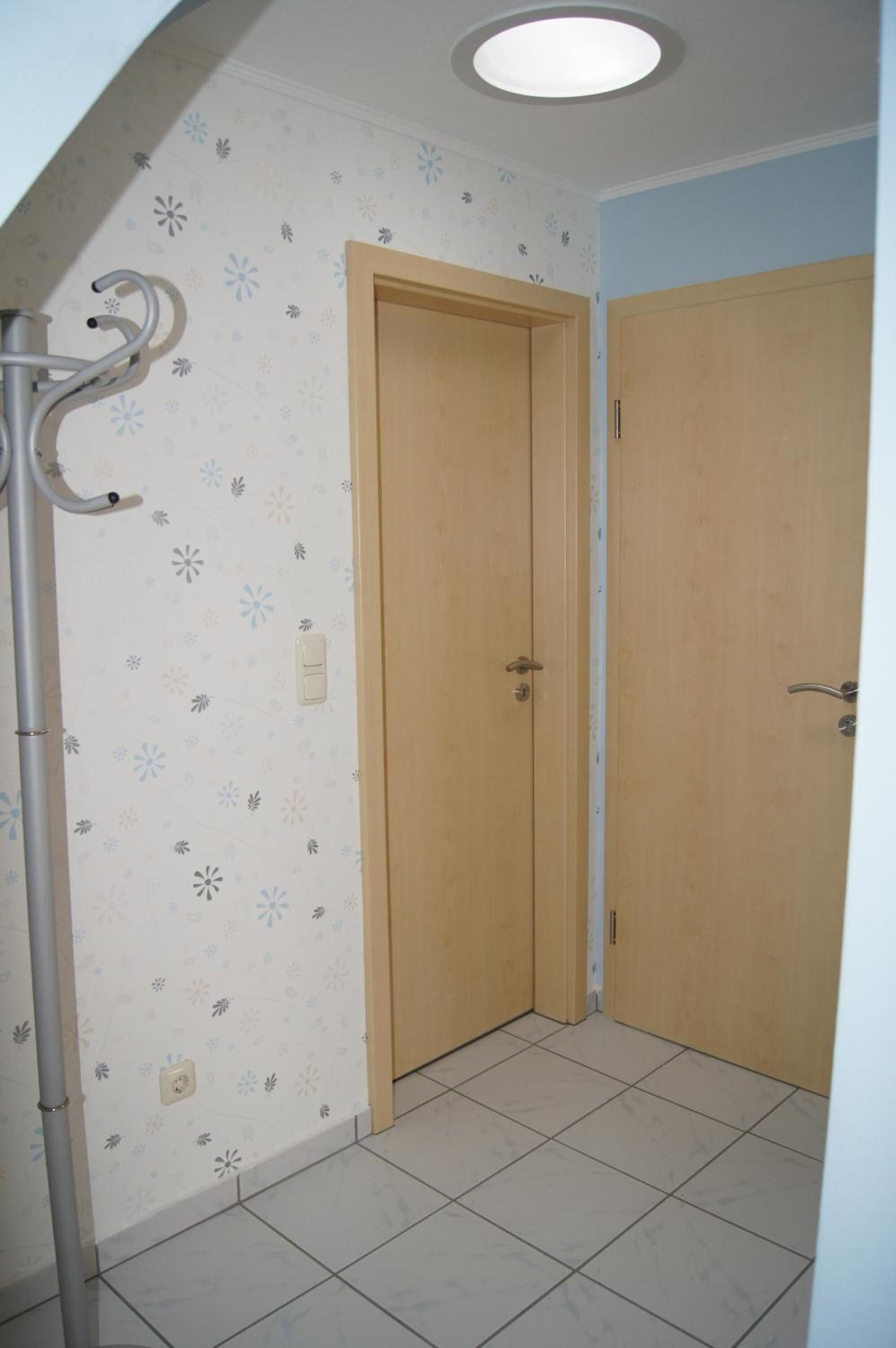 A room with two wooden doors, a light switch, and a ceiling light fixture.