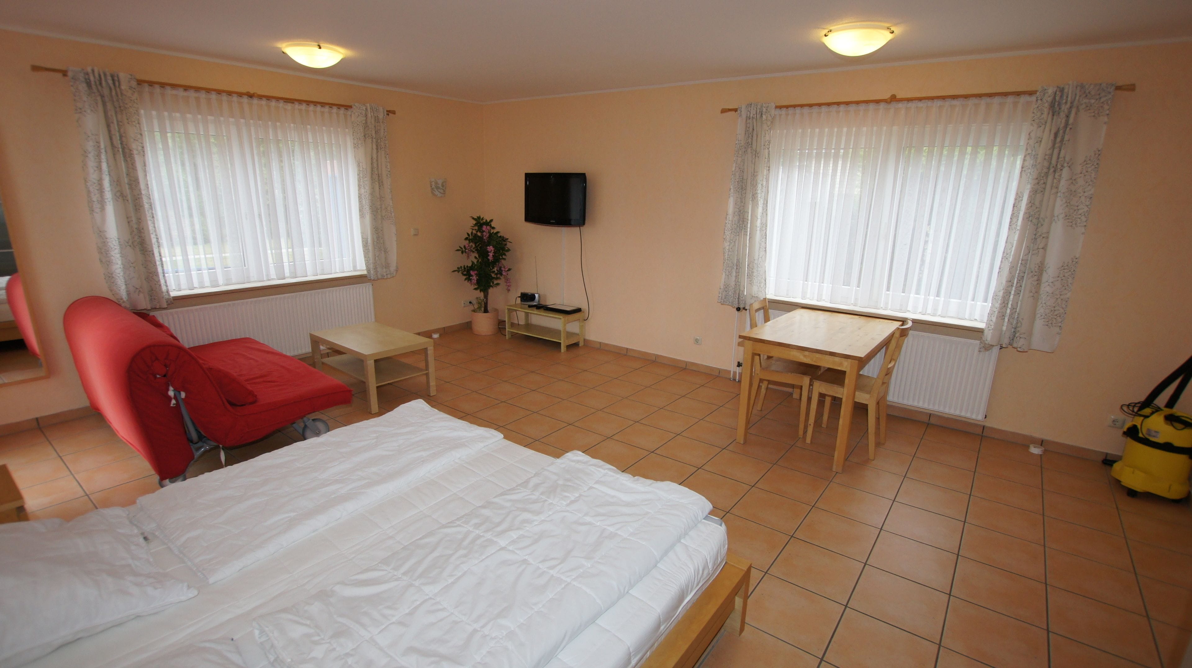 Ein Hotelzimmer mit Bett, Schreibtisch, Stuhl, Fernseher und einem Fenster mit Vorhängen.