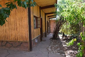 A wooden building with a stone pathway leading to a covered area. - Nxabii Cottages (Kasane)
