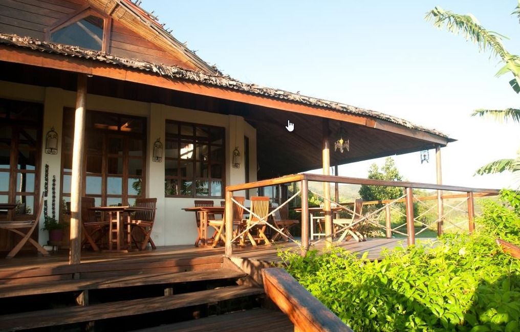 Eine Holzterrasse mit Sitzgelegenheiten im Freien, einem überdachten Bereich und Blick ins Grüne.