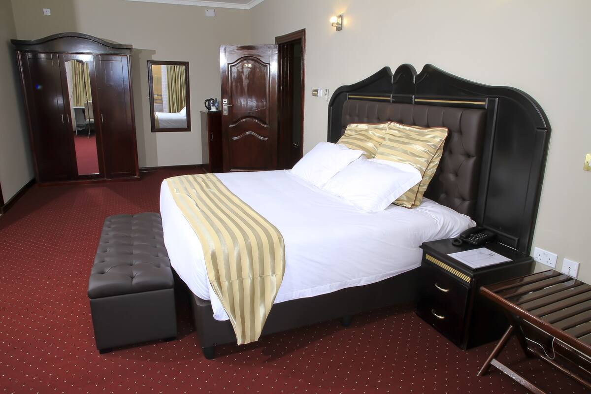 Een hotelkamer met een groot bed, een nachtkastje, een kledingkast en een spiegel.