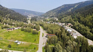A small town with a main road, surrounded by dense forests and hills. - The Burfield (Sun Peaks)