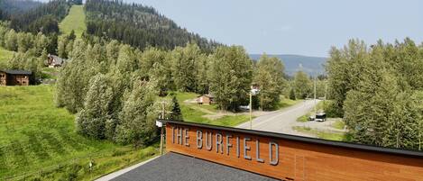 A view of The Burfield, featuring a wooden facade, a paved road, and surrounding greenery.
