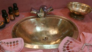 A bathroom sink with a faucet, a bowl, and several bottles of soap. - Riad El Bellar (Marrakech)