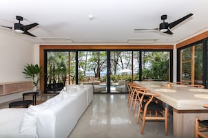 Uma sala de jantar moderna com uma mesa comprida, sofá branco e ventiladores de teto.