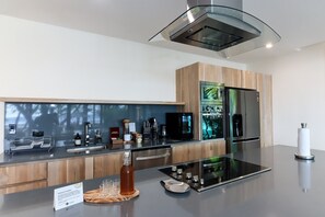 A modern kitchen with a central island, stainless steel appliances, and a wooden backsplash.