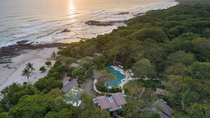 Eine Luftaufnahme eines Resorts mit Schwimmbad, direktem Strandzugang und üppiger Vegetation.