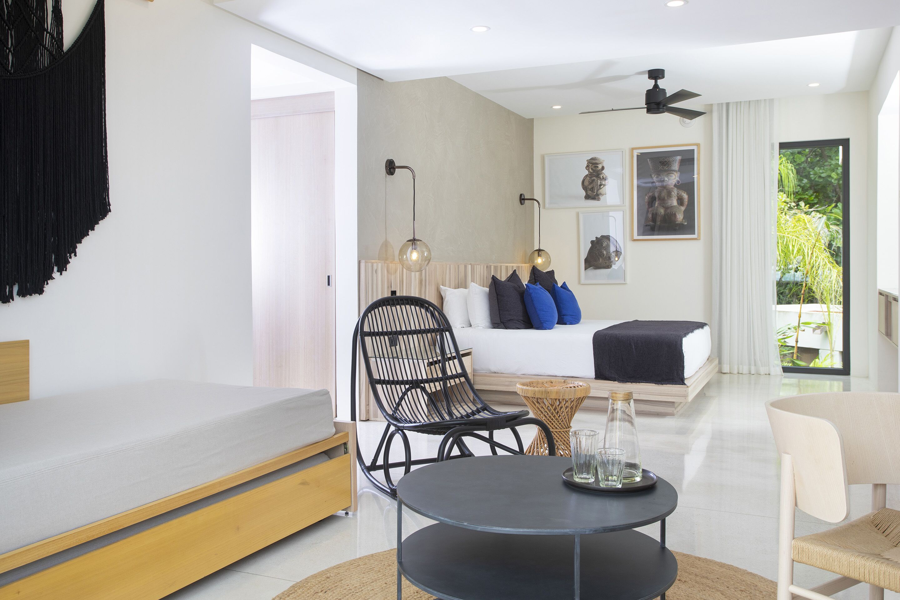 A modern hotel room with a bed, a dining table, a sofa, and a chair.