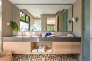 A modern bathroom with a large mirror, two sinks, and a wooden vanity.