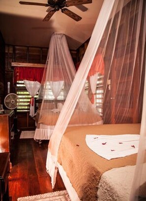 Quarto com cama, ventilador de teto e janela com cortinas.