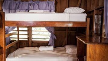 A bunk bed room with a wooden structure, a small table, and a window with curtains.