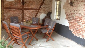 A rustic brick interior with a wooden table and chairs, a chalkboard menu, and a window with a view. - Landhaus Tewel (Neuenkirchen)