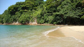 A beach with clear turquoise water and a sandy shore. - Canto Verde Aptos III (Caraguatatuba)