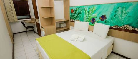 A hotel room with a bed, a desk, and a wardrobe.