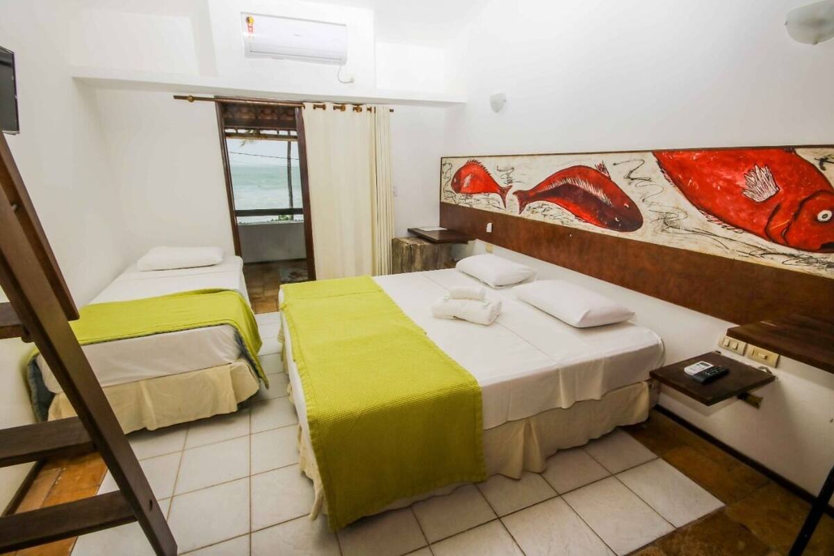 A hotel room with two beds, a painting of fish on the wall, a small table with a phone, and a window with curtains.