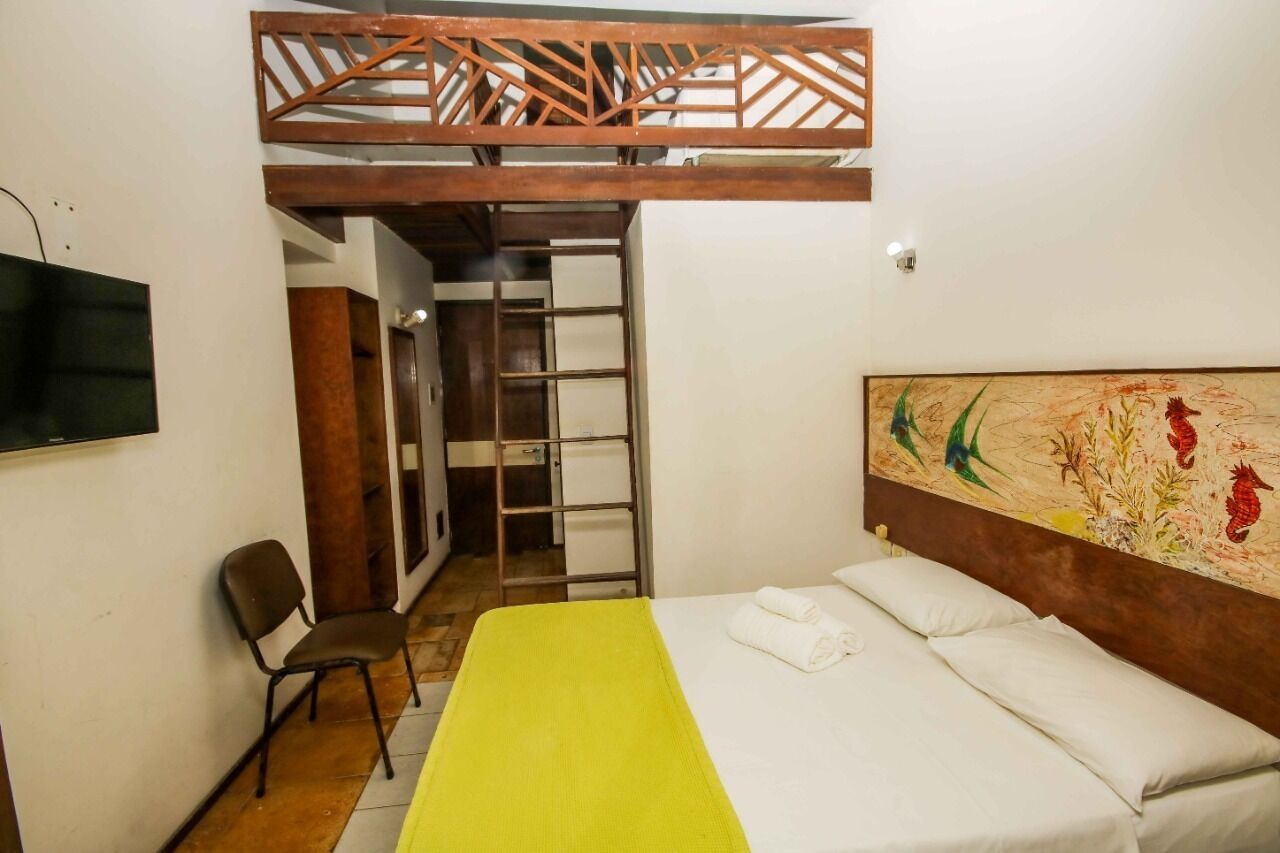 Una habitación con una cama, una silla, un televisor y un cuadro en la pared.