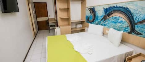 Habitación de hotel con cama, televisión, armario y un cuadro de un pájaro en la pared.