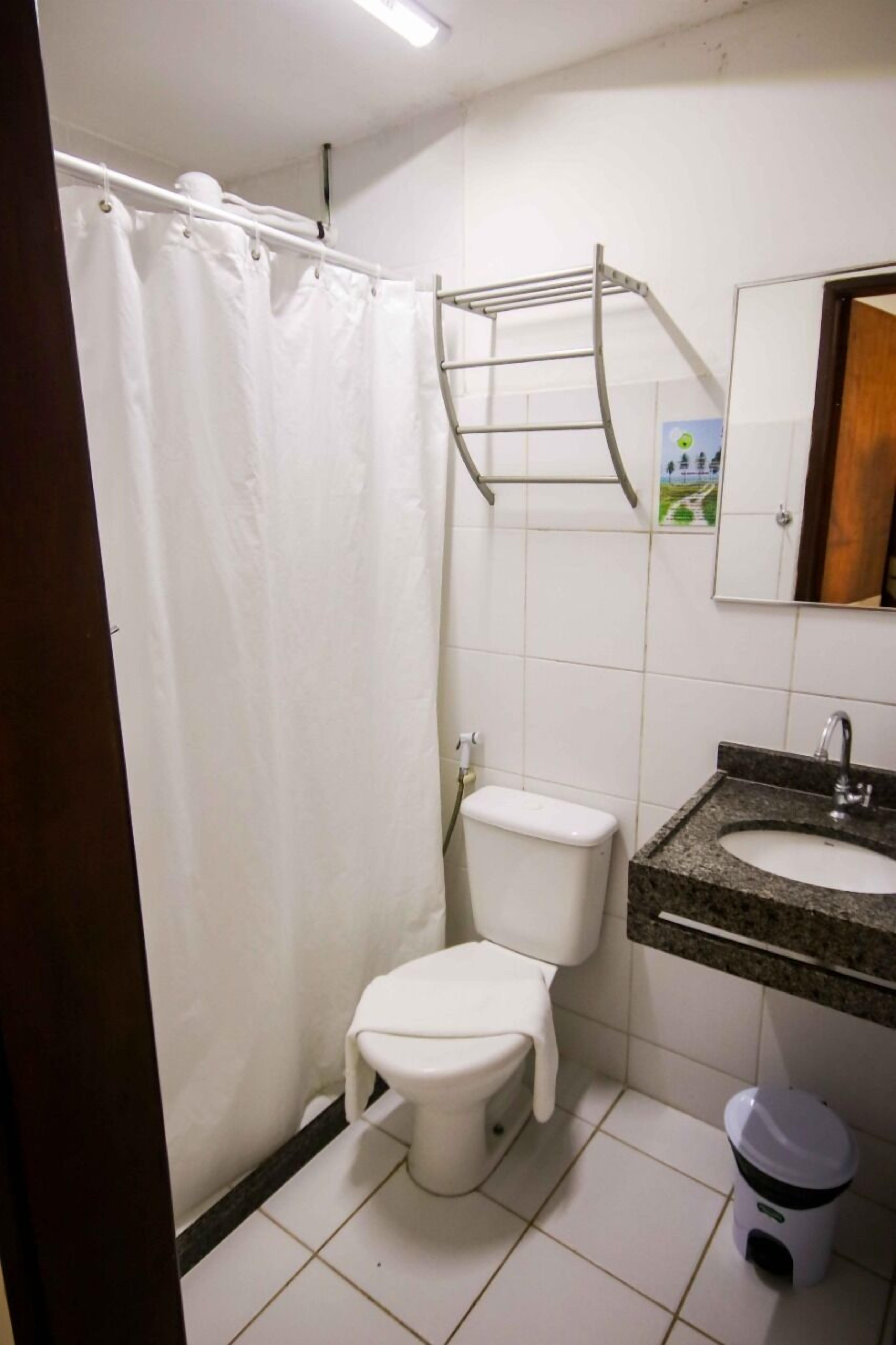 A bathroom with a toilet, sink, and shower curtain.