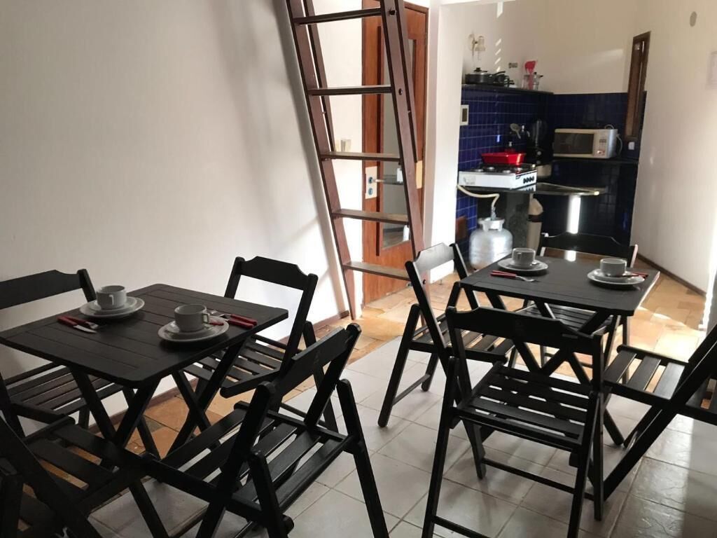 Un comedor con una mesa y sillas, una cocina al fondo y una puerta que da al exterior.